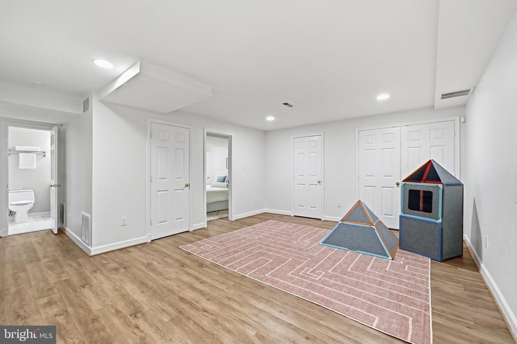 Finished basement playroom with a pink patterned rug and two fabric play tents.