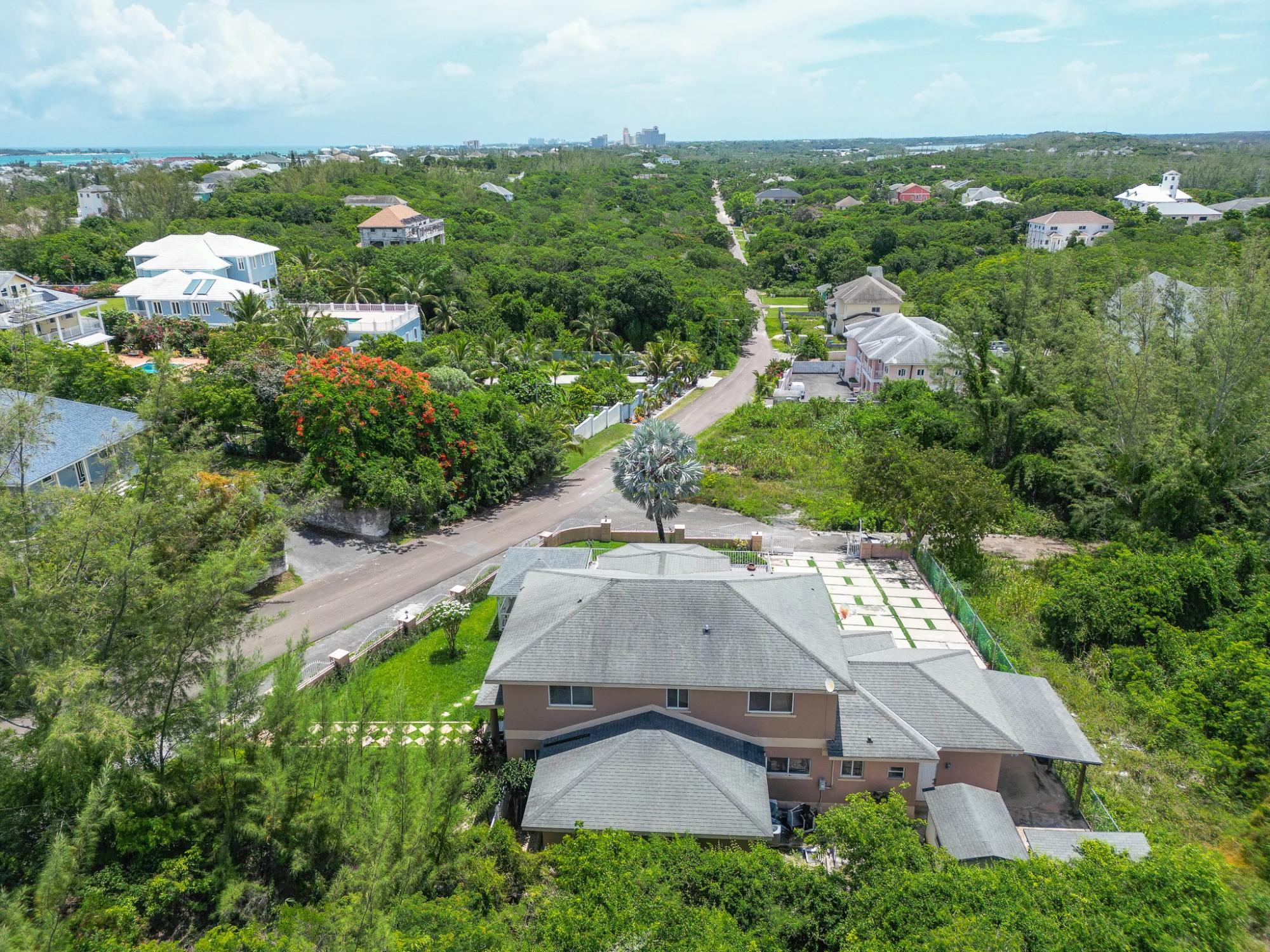Aerial view of a Westridge home amid tropical greenery, with nearby houses and distant water.