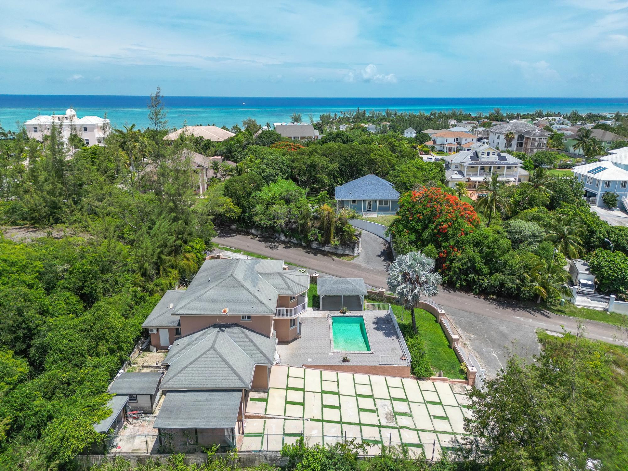 Aerial view of a Westridge home with a swimming pool, tropical neighborhood, and ocean beyond.