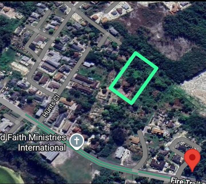 Aerial map showing a wooded parcel outlined in green beside Fire Trail and Hunts Cl.