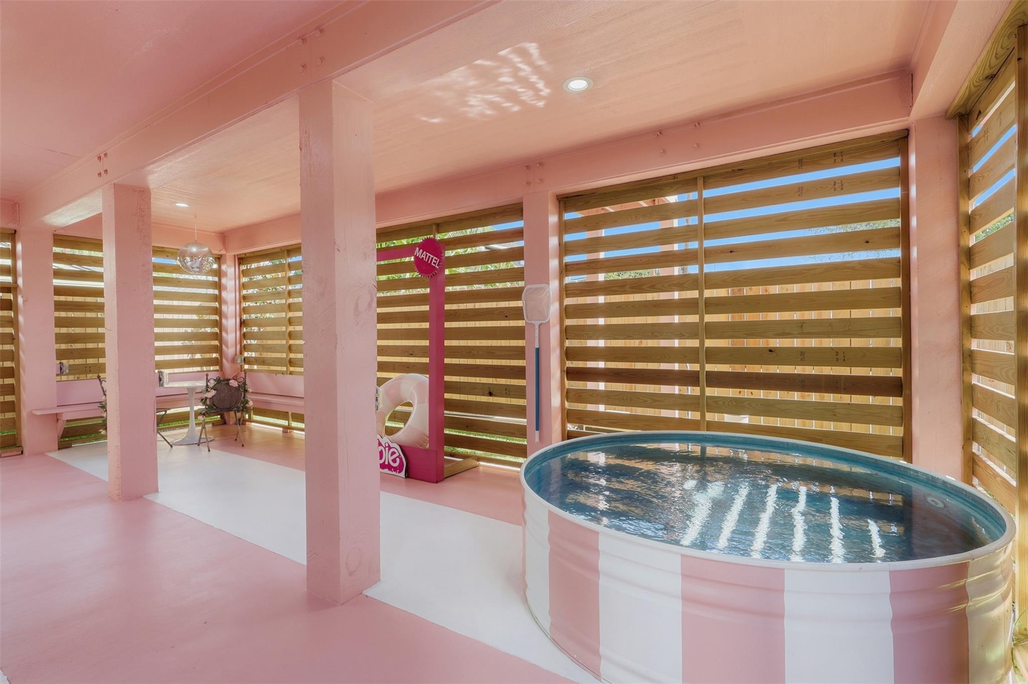 Pink indoor pool with striped sides in a play area with wooden slat walls.