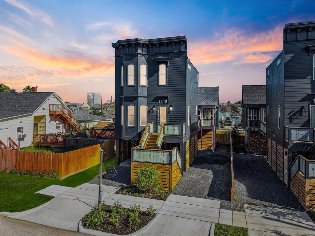 Dark modern home marked 1112, with a raised porch and front steps at sunset.