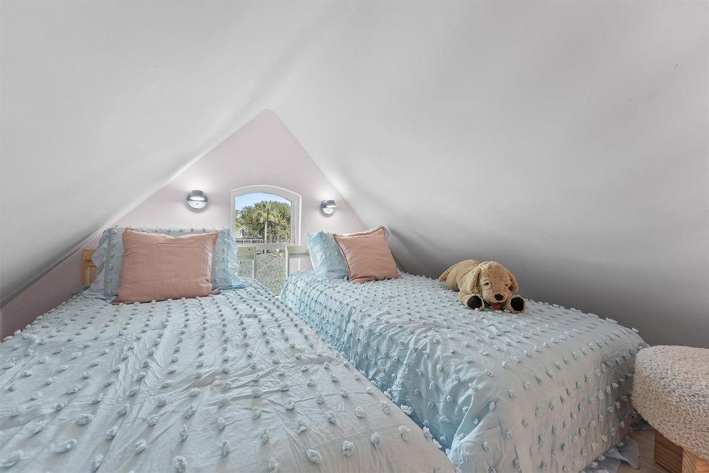 Attic bedroom with two pale blue beds, a dormer window, and a plush dog.