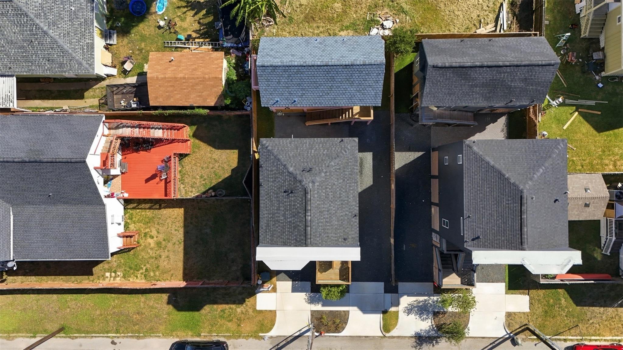 Aerial view of closely spaced houses and yards, including a neighboring home with a red deck.