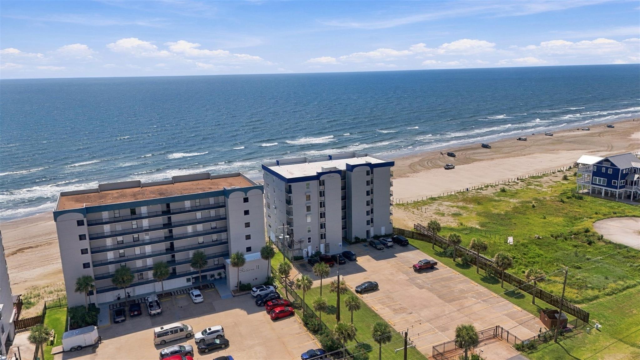 Beachfront condominium complex beside the Gulf, viewed from above with ocean and sandy beach.
