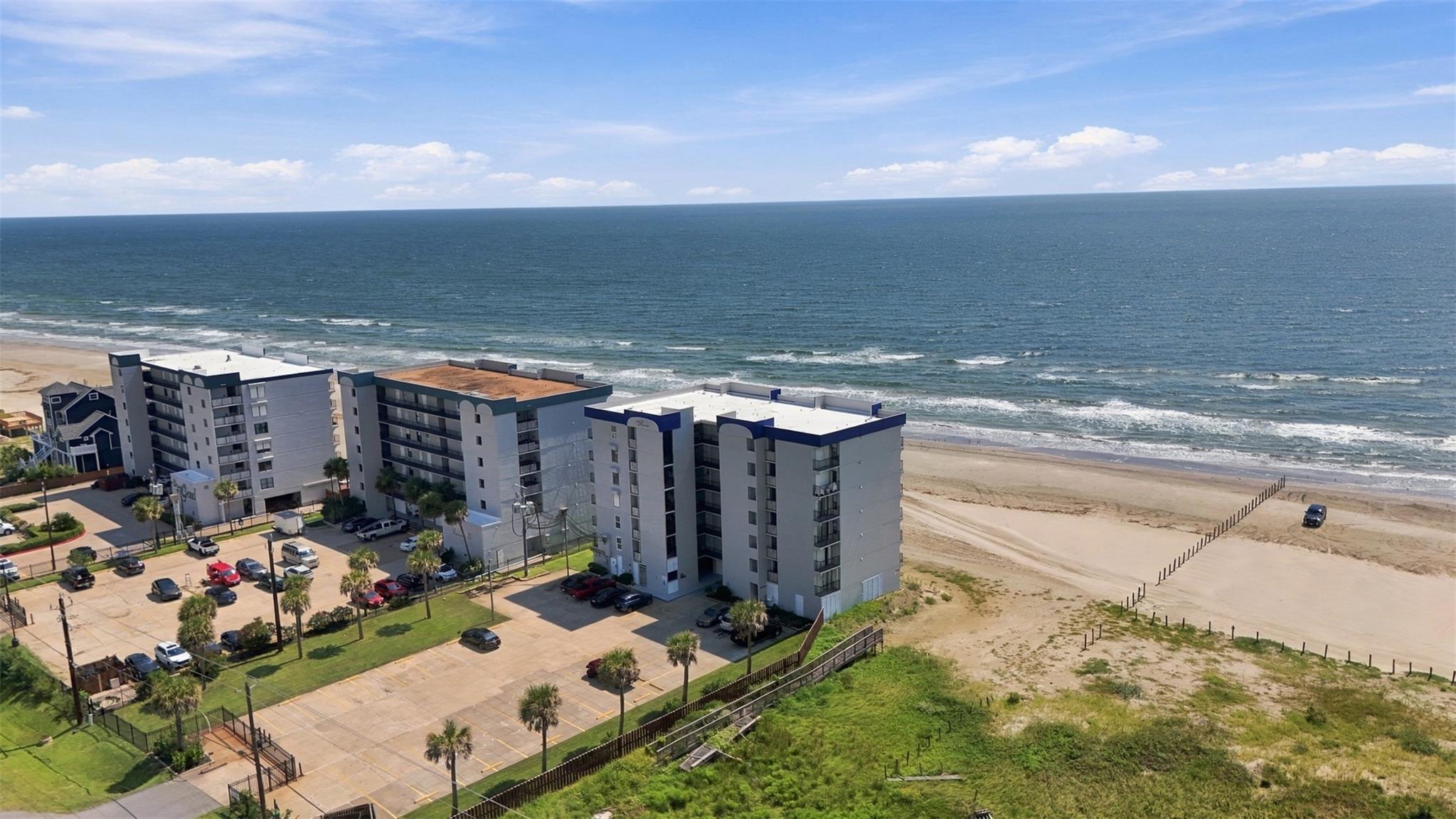 Beachfront condominiums beside a sandy shore, with the Gulf of Mexico stretching across the horizon.