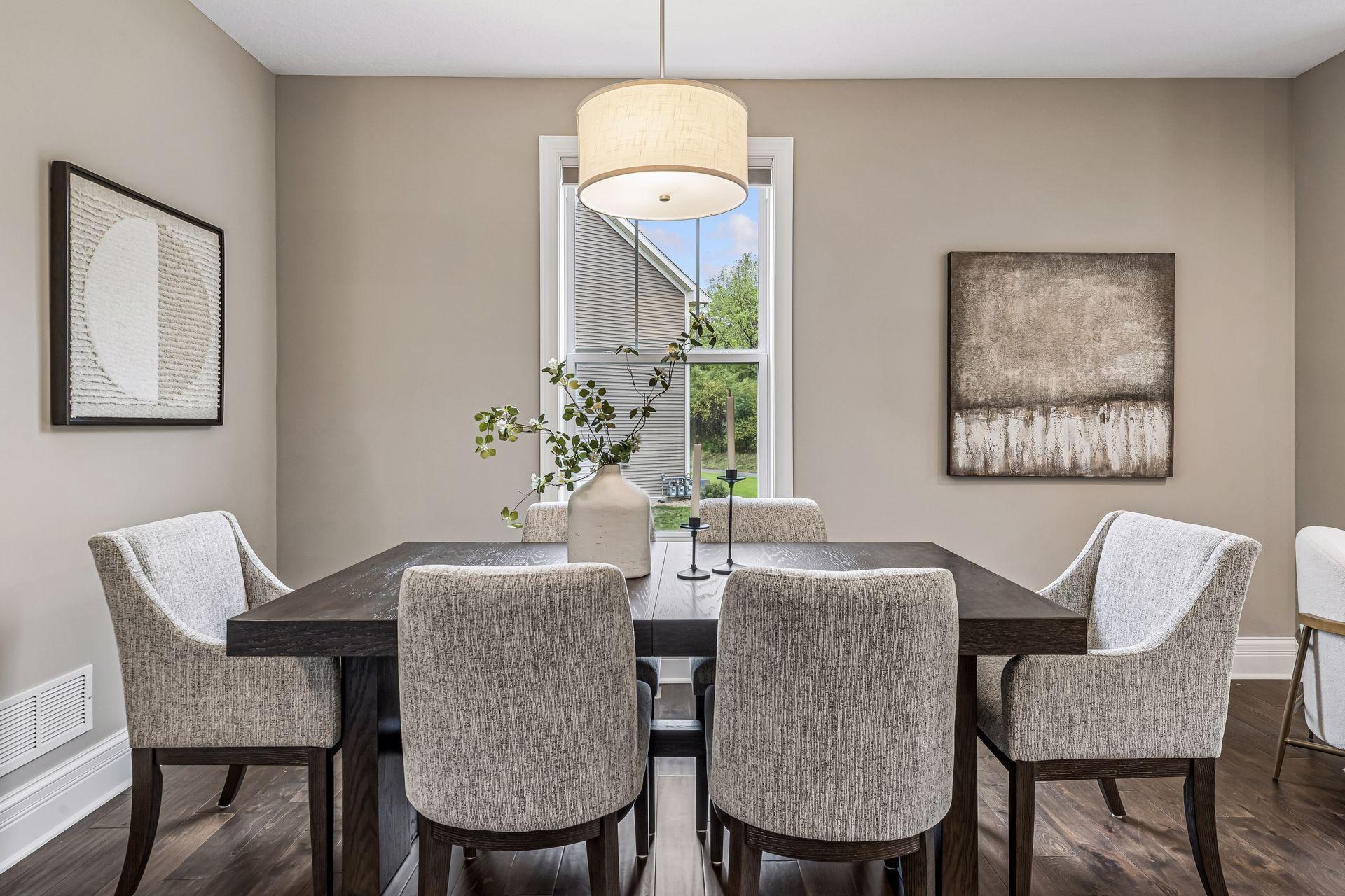 Dining room with a dark wood table, upholstered chairs, and a large pendant light.