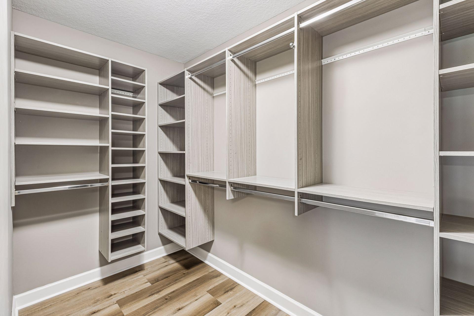 Walk-in closet with built-in shelves and hanging rails, finished with light wood cabinetry and plank flooring.