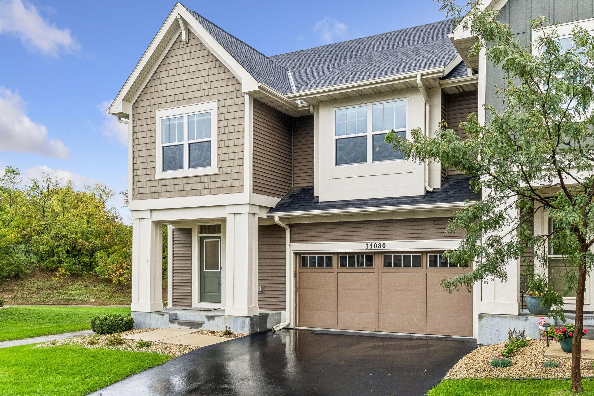 Two-story attached home with white-trimmed windows, covered entry, and attached garage.