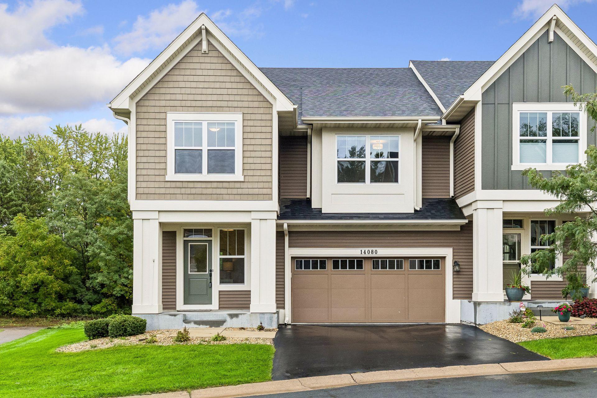 Two-story home with beige and gray siding, green front door, and double garage marked 14080.