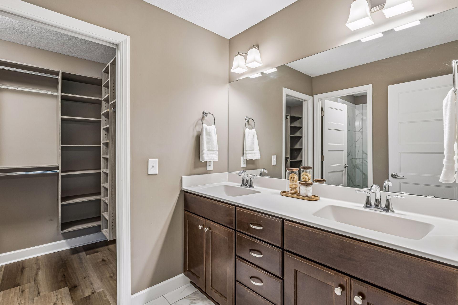 Bathroom with a double-sink vanity and open walk-in closet.