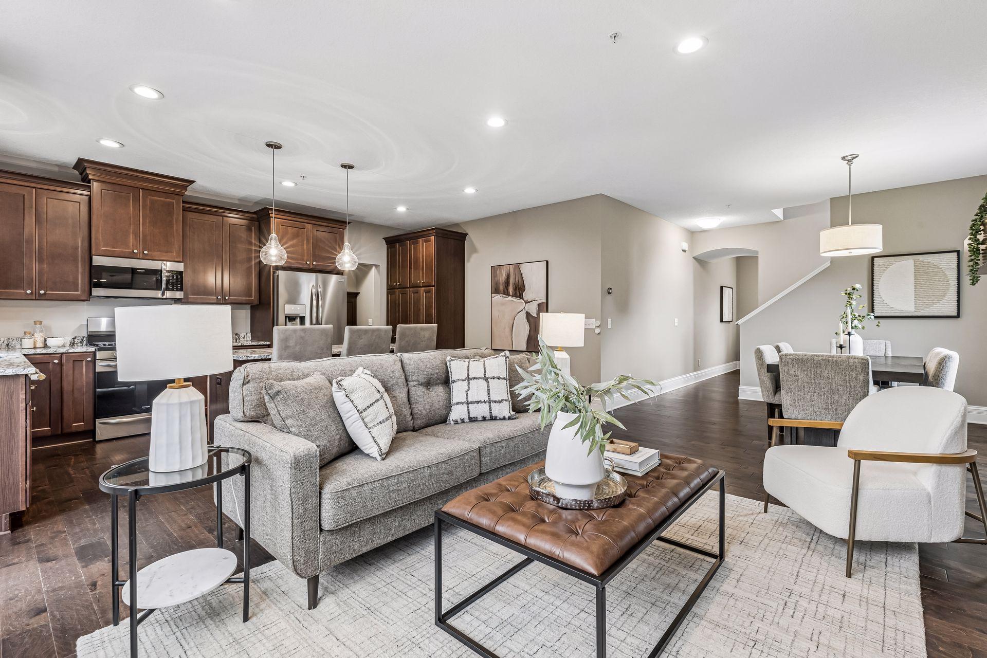 Open-plan living room with gray sofa, dark wood kitchen cabinets, and adjoining dining area