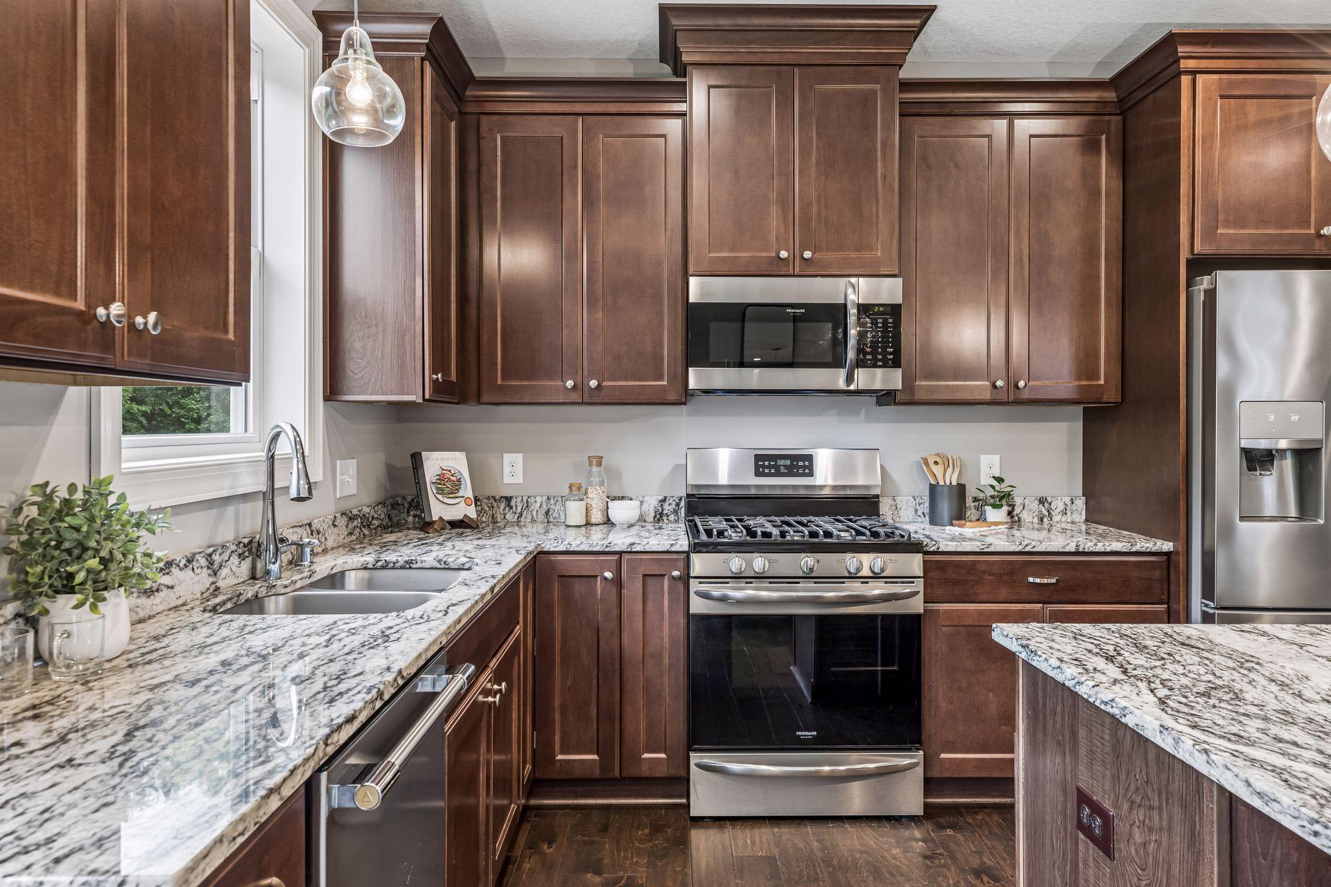 Kitchen with dark wood cabinets, veined granite counters, stainless steel appliances, and a gas range.
