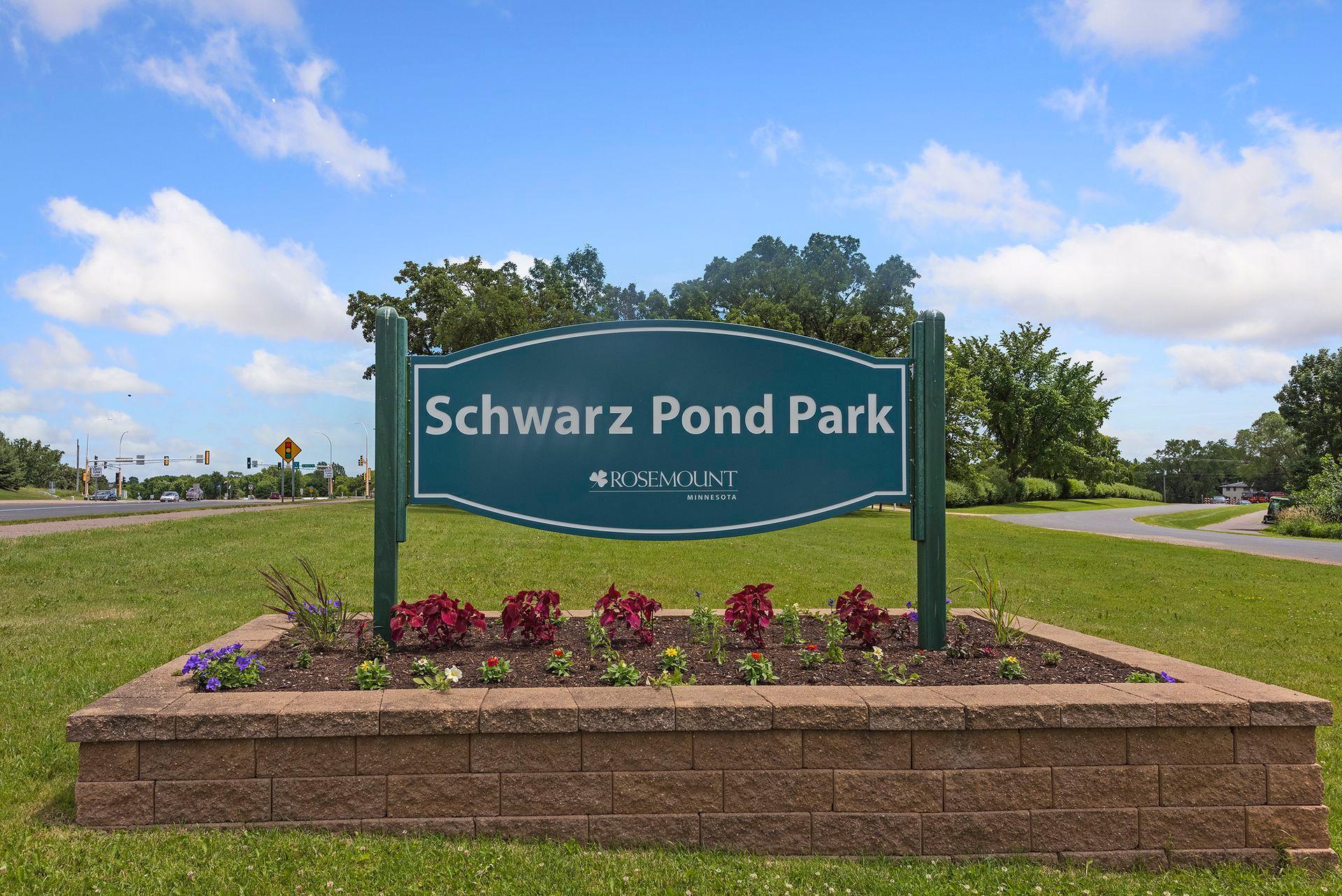 Schwarz Pond Park sign in Rosemount, set in a landscaped flower bed beside the road.