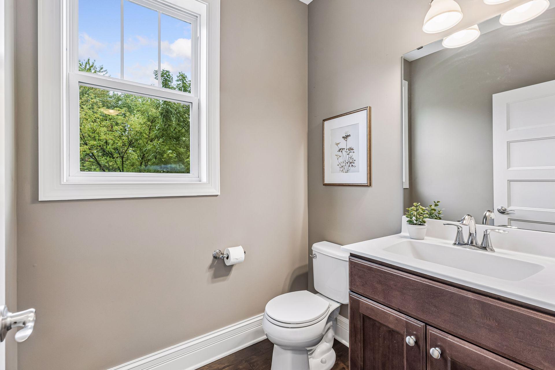 Bathroom with a dark wood vanity and large window overlooking leafy trees.