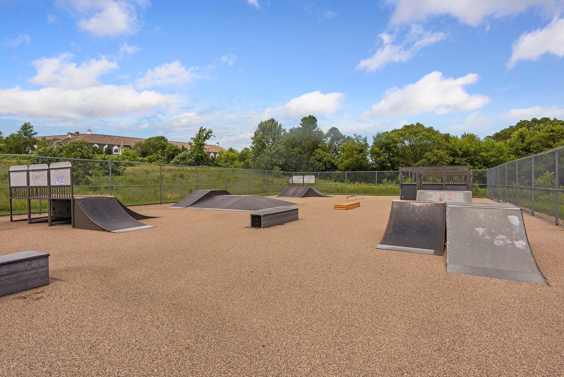 Outdoor skate park with fenced ramps, rails, and platforms.