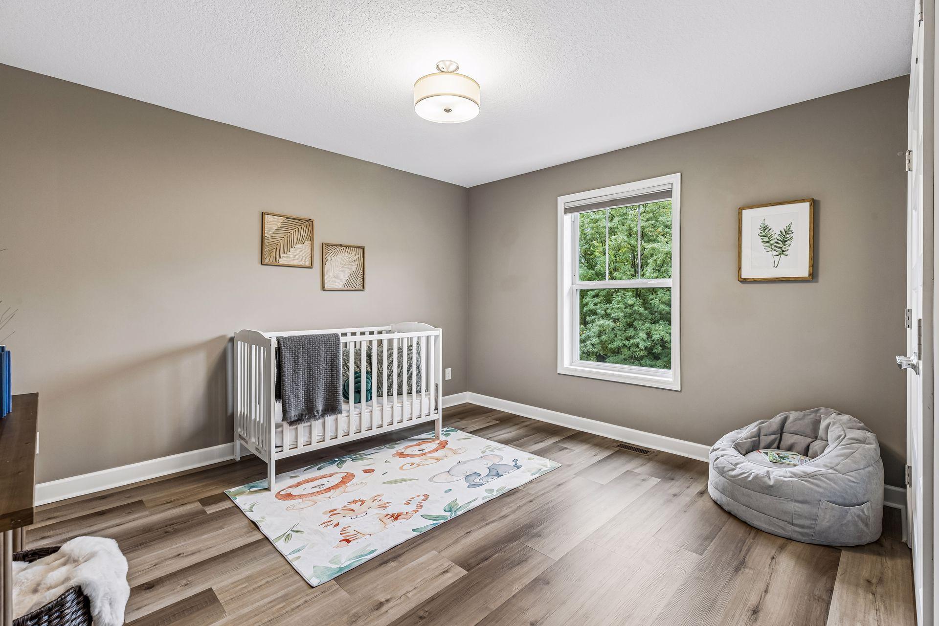 Nursery with a white crib, animal-print rug, and window overlooking greenery.