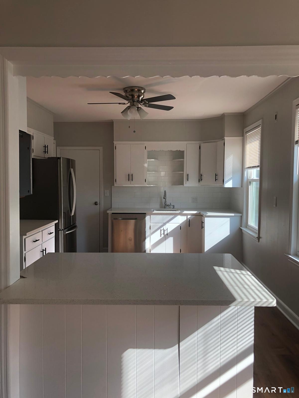 Kitchen with white cabinets, a large island, and sunlight streaming through the windows.