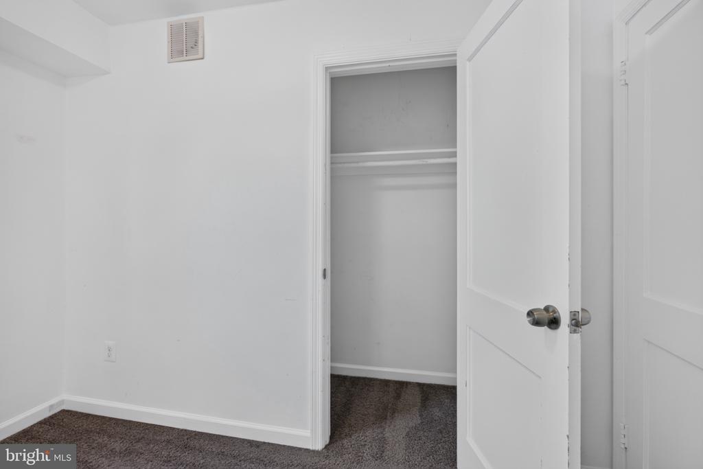 Empty carpeted room with an open closet and white door.