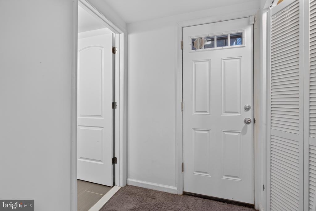 Entry foyer with a white front door, narrow upper window, and louvered closet.