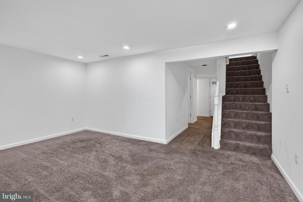 Finished basement with carpeted floor and staircase.