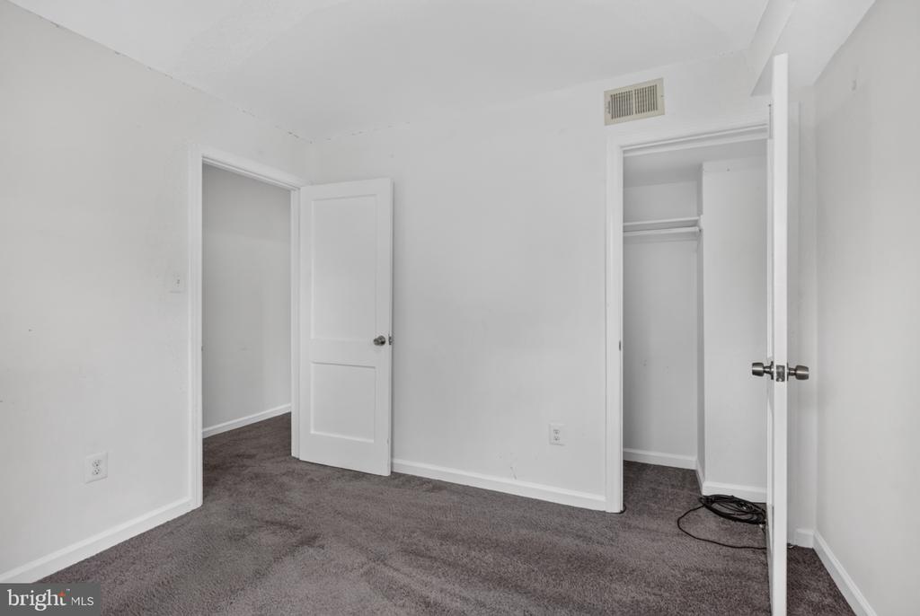 Empty bedroom with gray carpet and an open closet door.