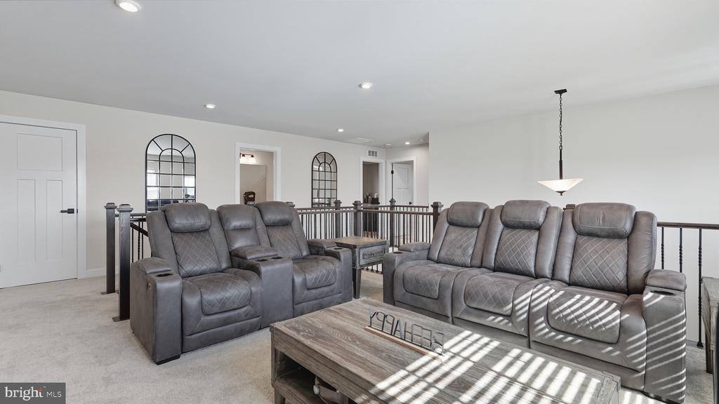 Upstairs living area with gray reclining sofas, a wood coffee table, and a black railing.