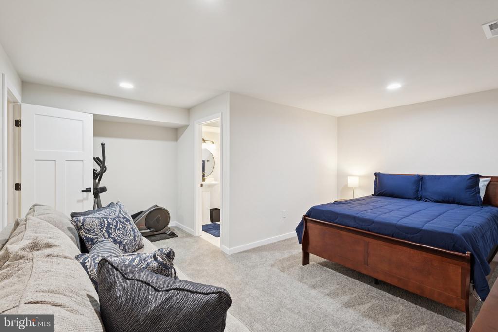 Bedroom with a navy bed, sofa, and exercise equipment.