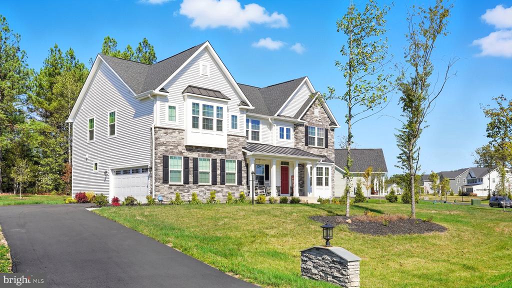 Two-story white house with stone accents, a red front door, and a wide driveway.