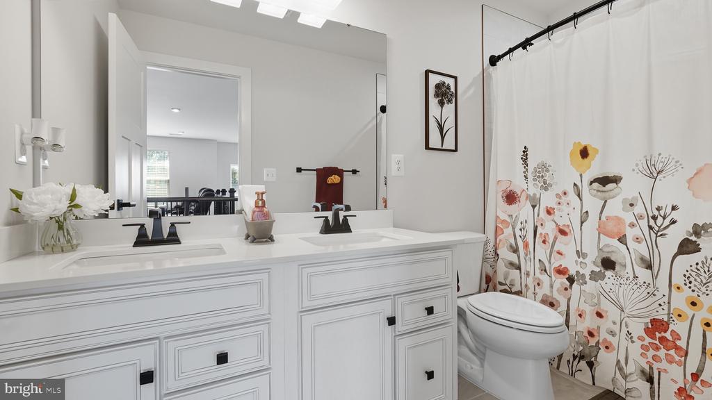 Bathroom with a white double-sink vanity, large mirror, and floral shower curtain.