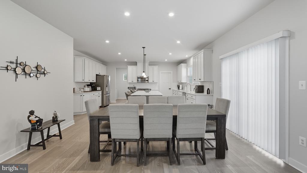 Open-plan dining room and kitchen with white cabinets, a central island, and a gray dining set.