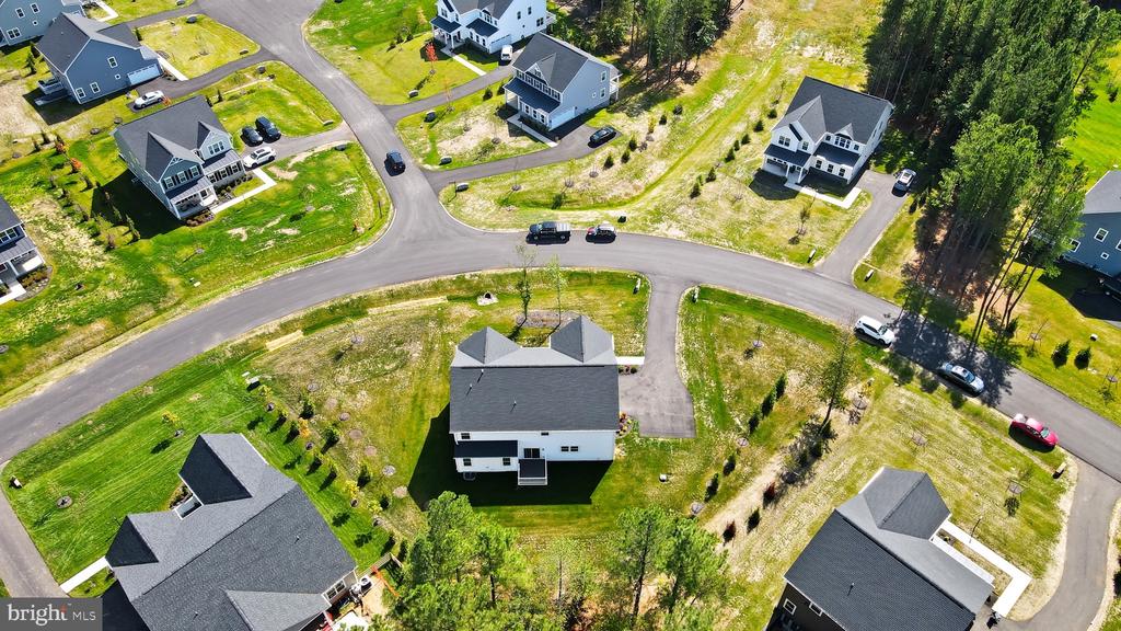 Aerial view of a white house on a green lot among neighborhood homes and curving streets.
