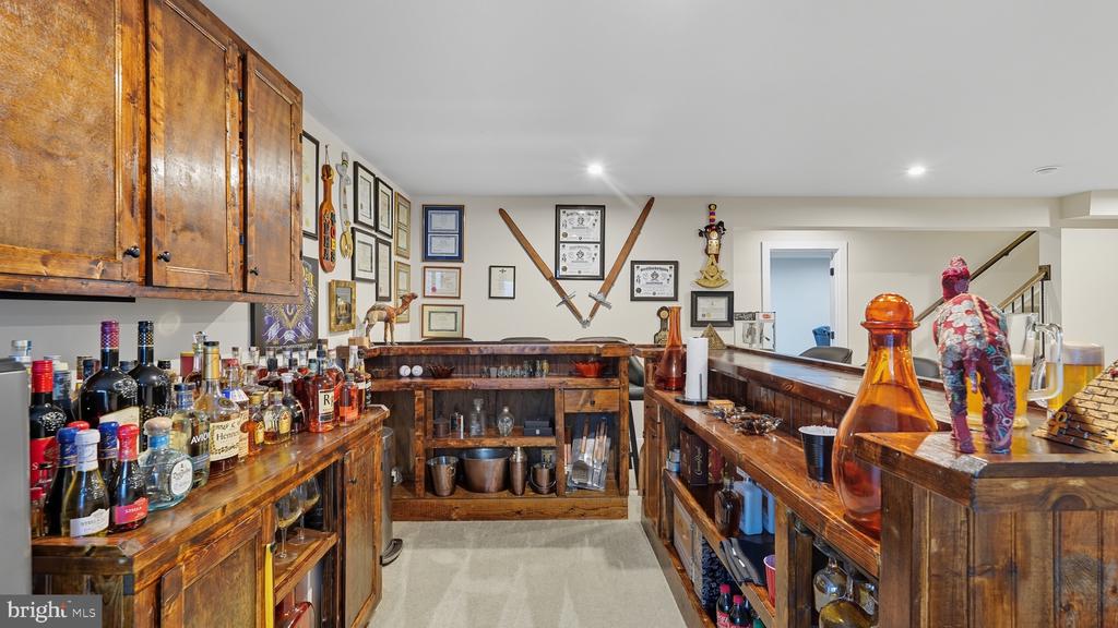 Home bar with wooden counters, bottle displays, and swords mounted on the wall.