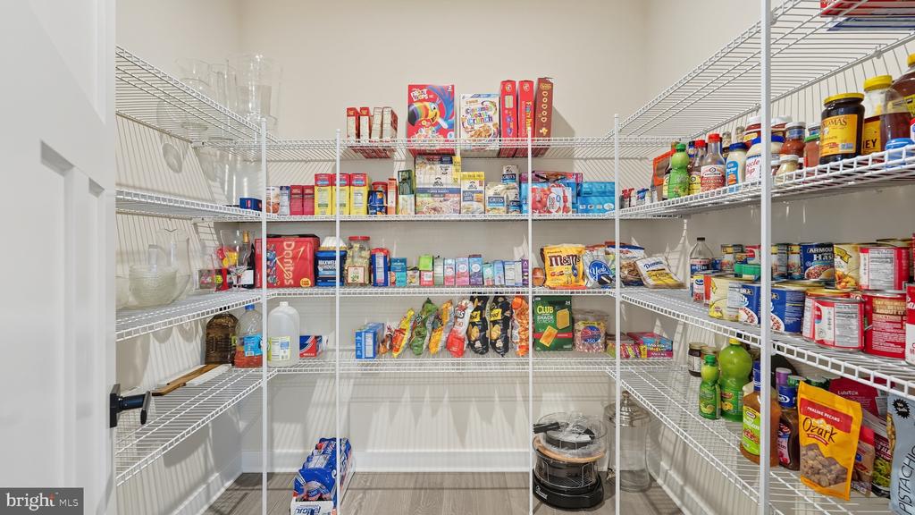Walk-in pantry with wraparound wire shelving stocked with groceries and snacks.
