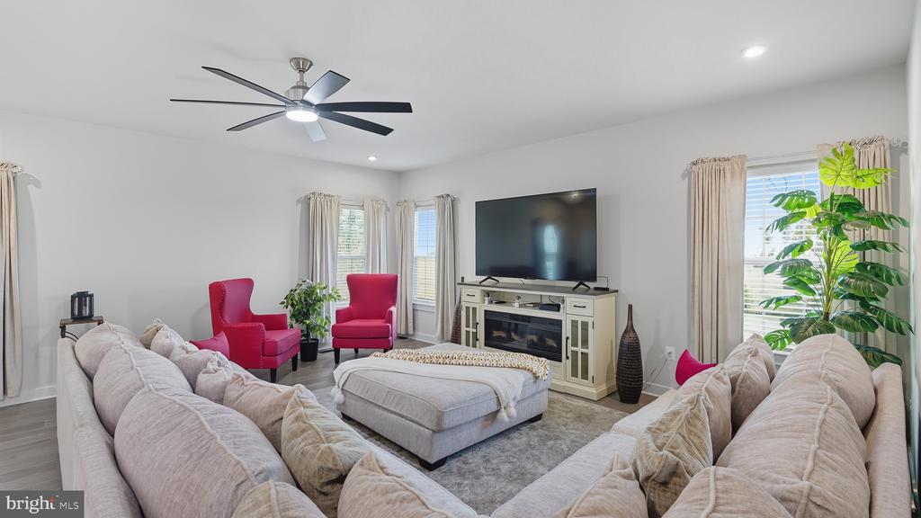 Furnished living room with a large sectional, red accent chairs, and a television above the fireplace.