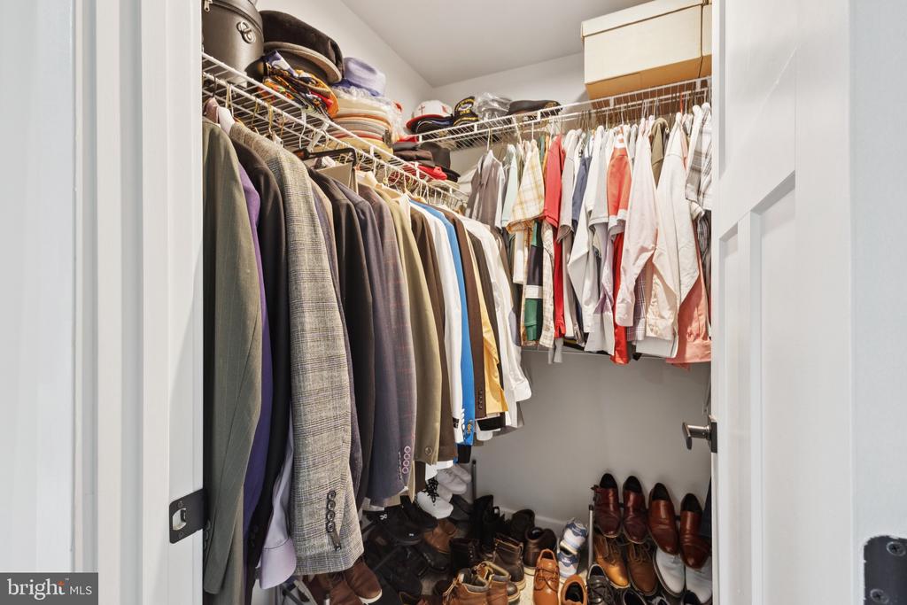 Walk-in closet filled with hanging clothes, storage bins, and rows of shoes.