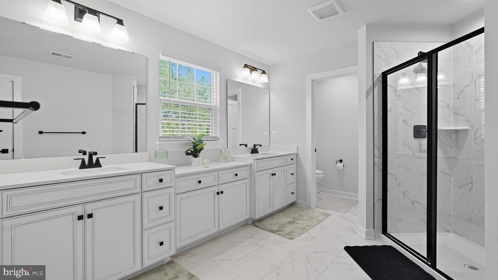 Bathroom with a white double vanity and a black-framed glass shower with marble-look tile.