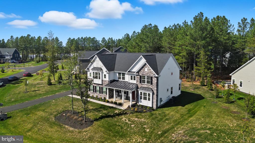 Aerial view of a two-story white house with stone accents, dark roof, and broad lawn.