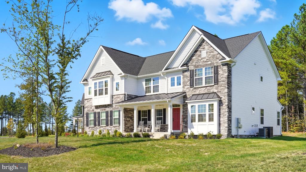 Two-story white-sided house with stone accents, a red front door, and a covered porch.