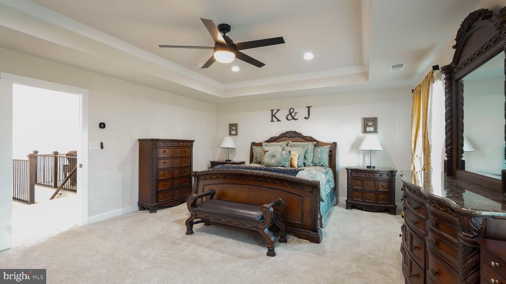Furnished bedroom with a carved wood bed, teal bedding, matching dressers, and an ornate mirror.