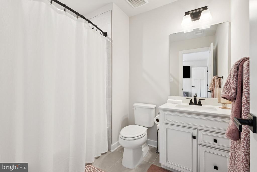 Bathroom with a white paneled vanity, black faucet, and shower curtain.