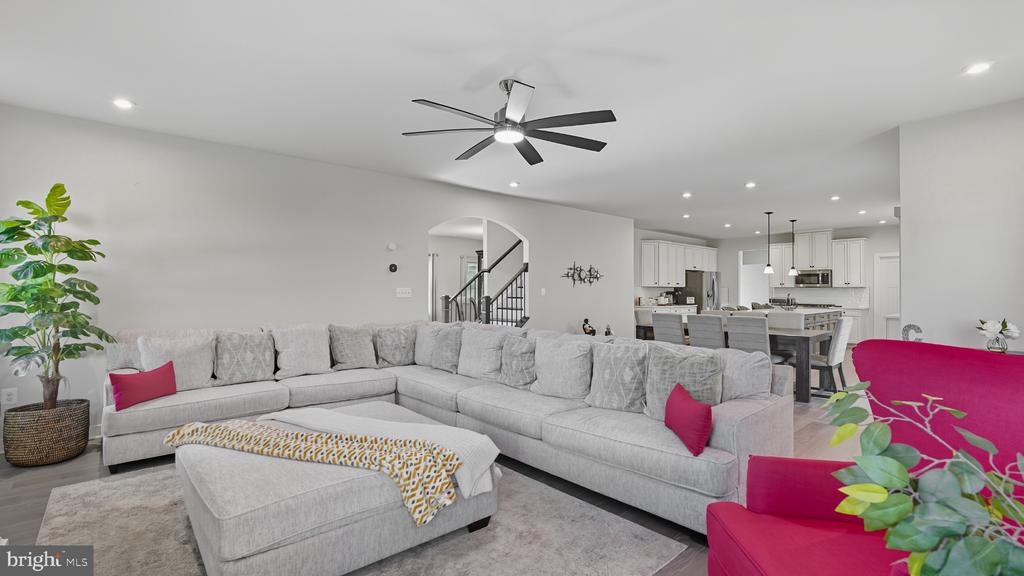 Living room with a light-gray sectional, pink accent chairs, and an open kitchen.