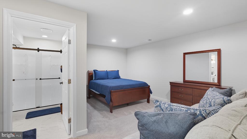 Furnished bedroom with a blue bed, dark wood dresser, and adjoining bathroom.