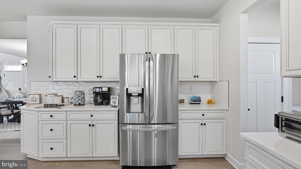 Kitchen with white paneled cabinets, stainless steel refrigerator, and a coffee bar.