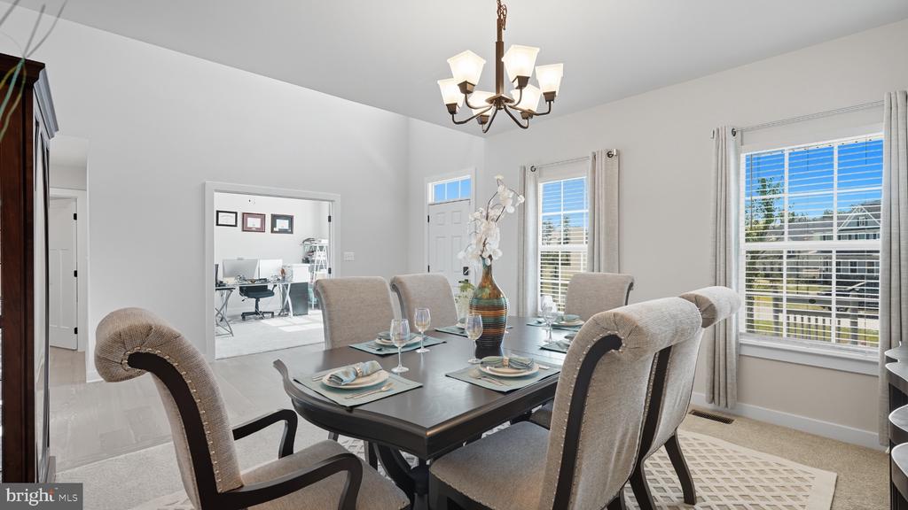 Dining room with a set table, upholstered chairs, chandelier, and large windows.