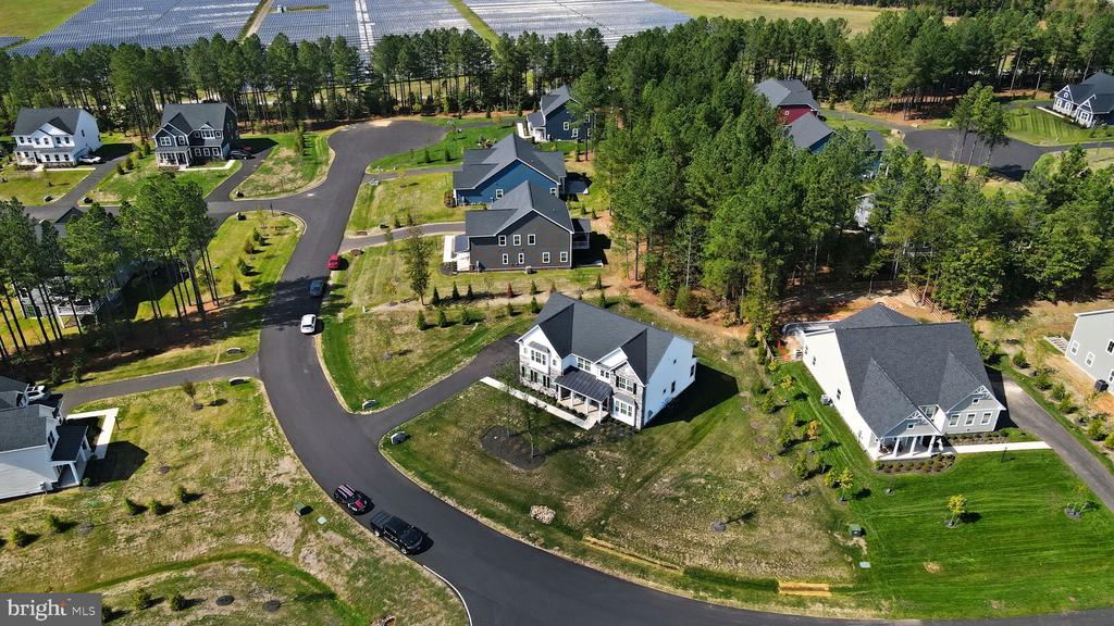 Aerial view of a white two-story house on a spacious lot in a wooded neighborhood.