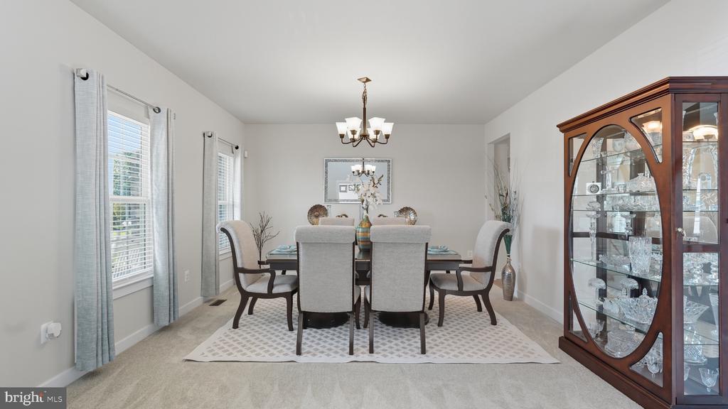 Dining room with upholstered chairs, a chandelier, and a glass-front china cabinet.