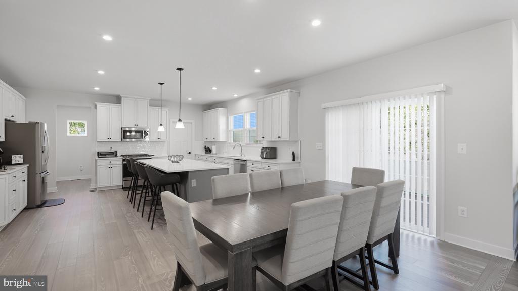 Open-plan kitchen and dining area with a large island, white cabinets, and a dining table.