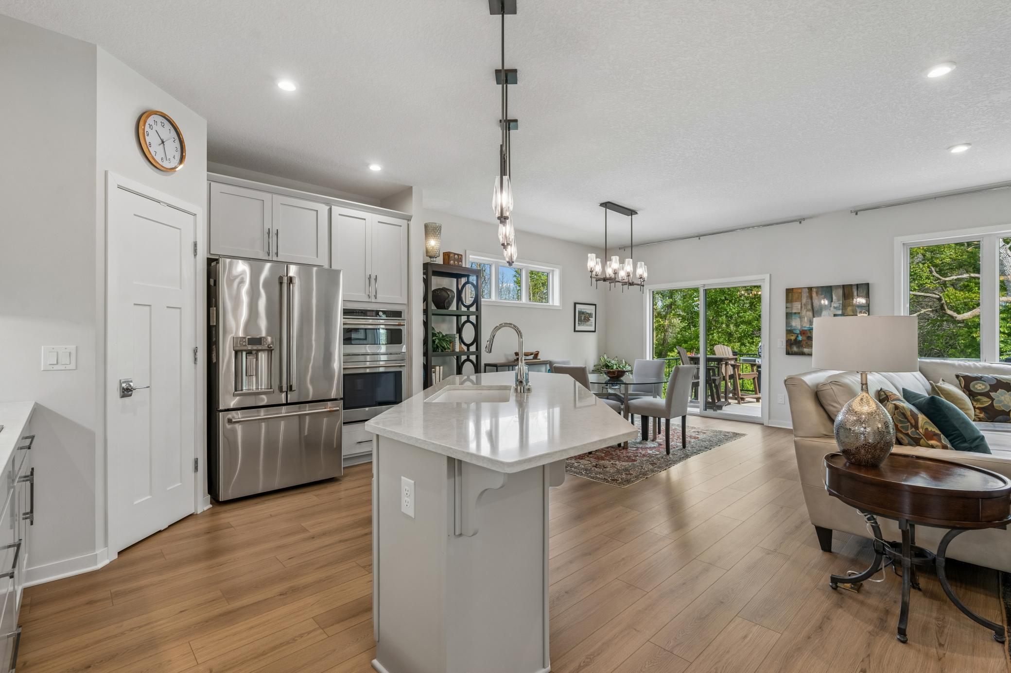 Open-plan kitchen and living room with a large island, stainless steel appliances, and glass doors to a patio.