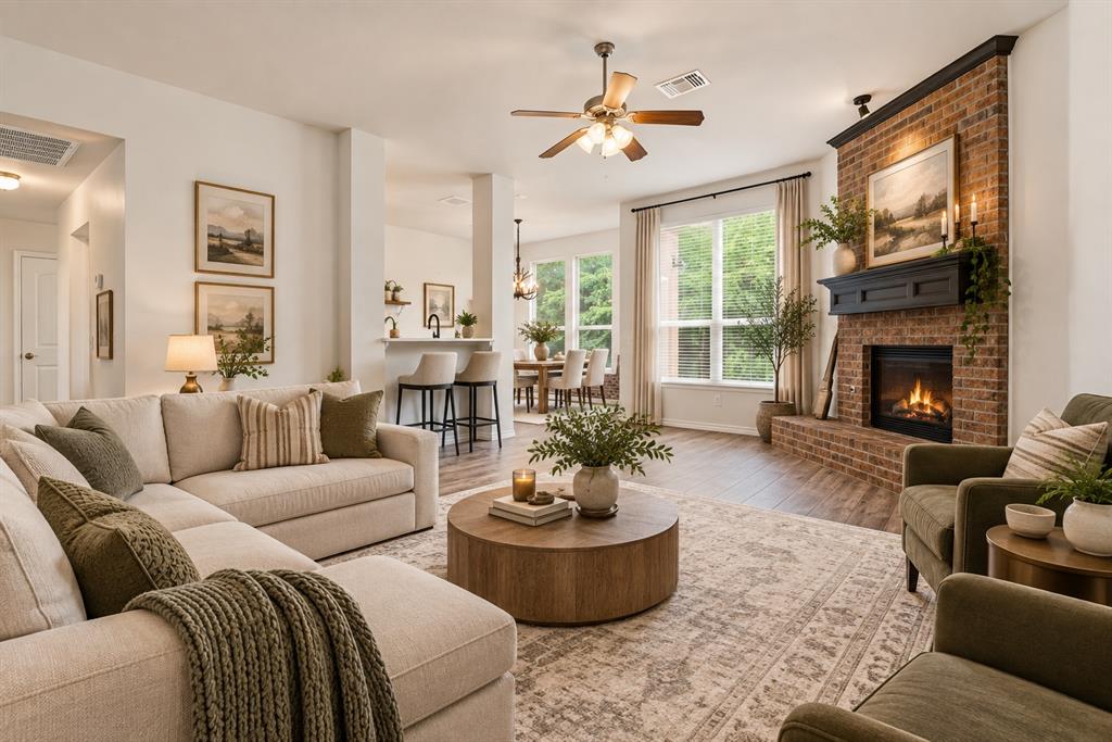 Staged living room with a brick fireplace, cream sectional, and open dining area.